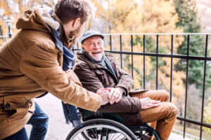 a carer and a person in need of care on wheelchair sharing a happy moment, looking at each other and smiling