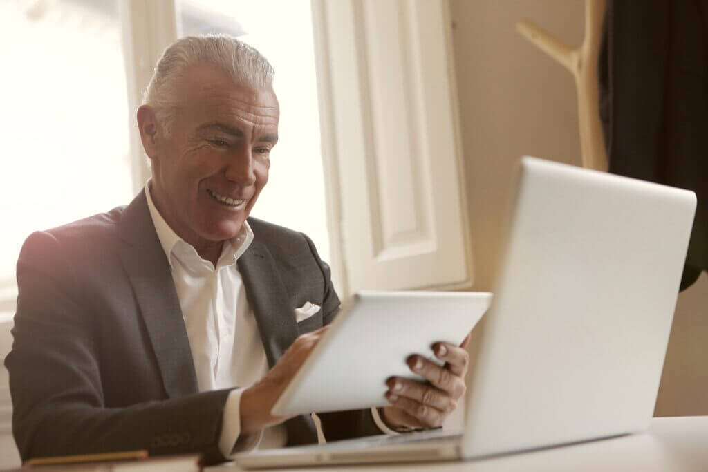 Older man working at laptop and tablet