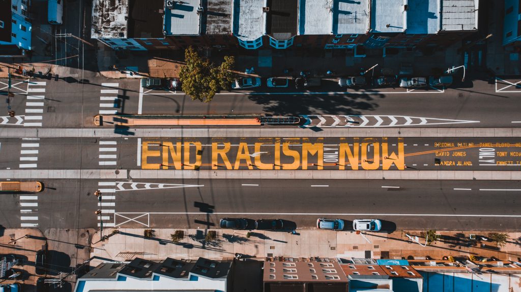 Bird's eye view of road with the letters 'End racism now' painted in yellow letters