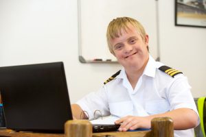 Man with learning disability and autism working on a laptop and wearing a police uniform