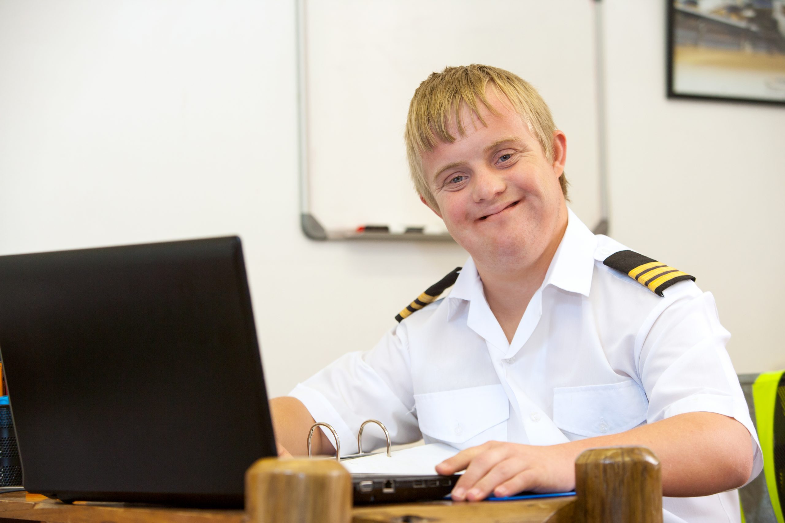 Man with learning disability and autism working on a laptop and wearing a police uniform