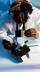 Black male scientist looking into microscope