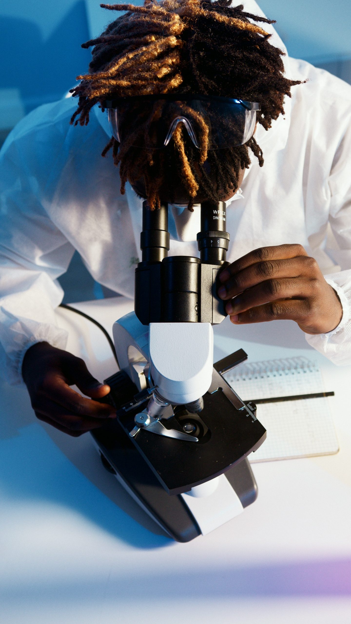 Black male scientist looking into microscope