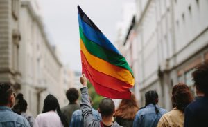 Person holding up Pride flag among crowd of participants