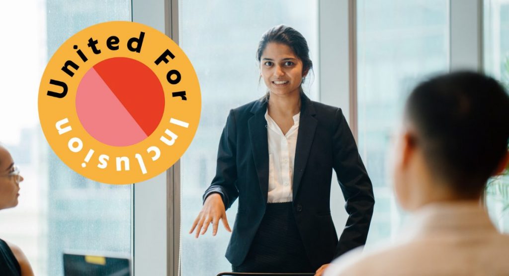 Person giving a talk about National Inclusion Week plans, with United For Inclusion button hanging in the background