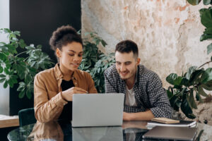 Two office workers reading the LGBTQ+ guide on their work laptop