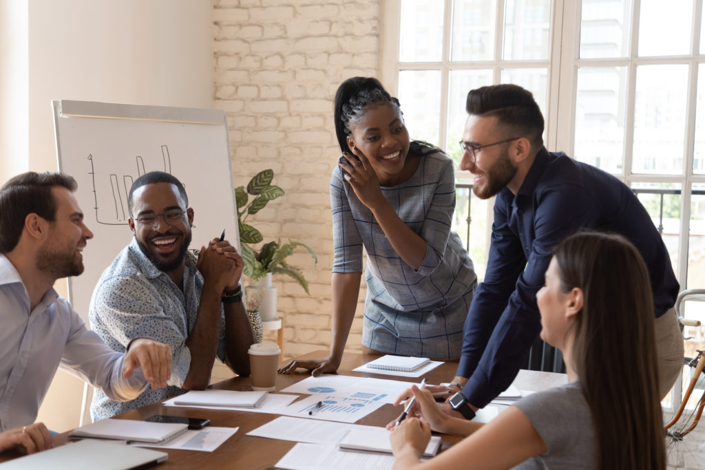 Diverse group of employees laughing together and working in the office
