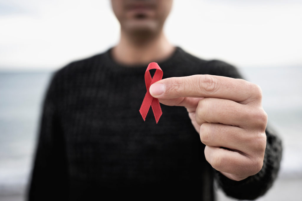 Person holding up red ribbon for World Aids Day