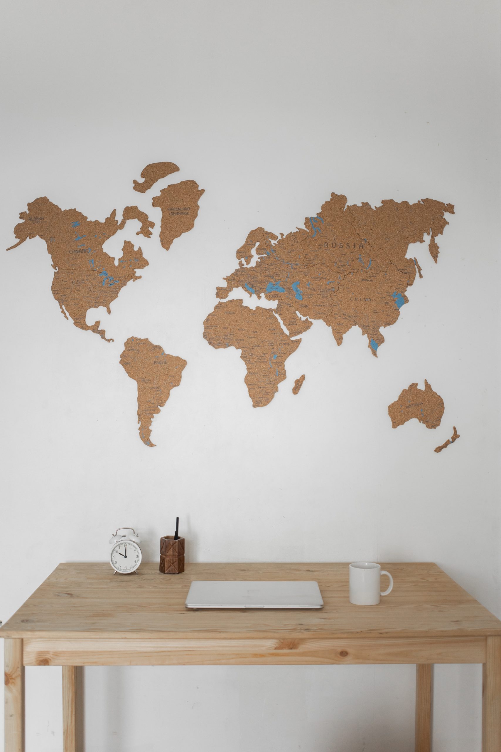 A map of the world, with the land in gold, on a blank white wall with a desk in front of it