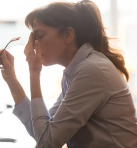Woman at work, resting her head in her hand, looking frustrated.