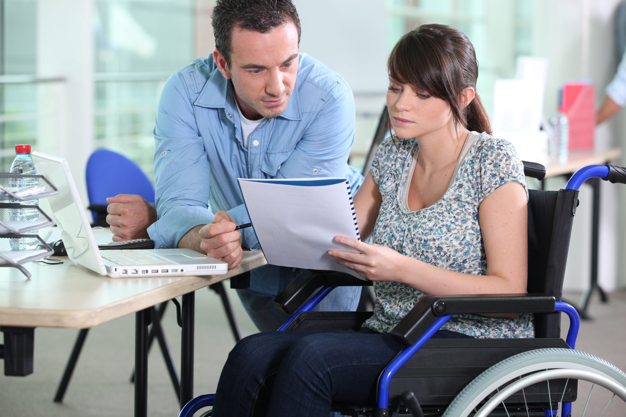 Wheel chair user going over notes with a colleague in the workplace