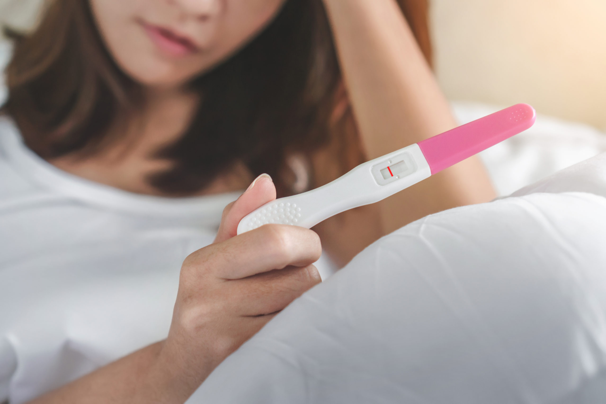 Person holding up a failed pregnancy test after experiencing baby loss