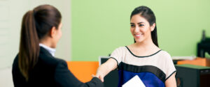 Two people shaking hands at a job interview. The interviewee is smiling.