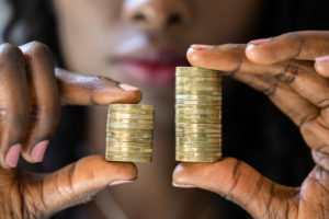 Person holding two stacks of coins, one higher than the other and one smaller than the other