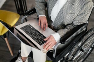 A wheelchair user with a laptop in their lap looking down on the screen
