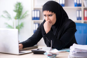 Female muslim office worker looking worriedly at her computer