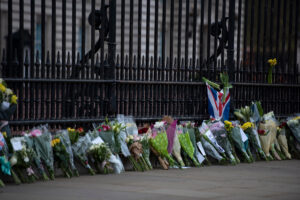 A shot of flowers being laid in front of Buckingham Palace