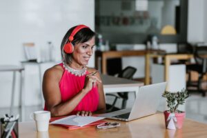 Transgender Latin woman wearing headphones and working at her desk