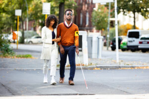 Black woman guiding a black man at an intersection