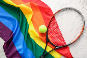 A tennis racket sitting on top of a LGBT+ pride flag