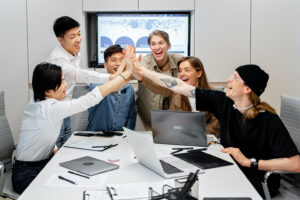 A diverse team high fiving in a meeting room