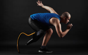 Side view of a Paralympian in sports wear , with a prosthetic leg, bending down ready to sprint