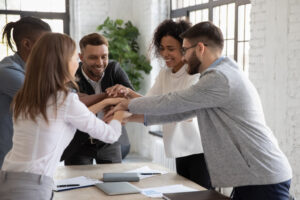 A diverse group of employees doing a high five in a meeting room