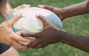 Rugby ball being held to by a pair of white and black hands