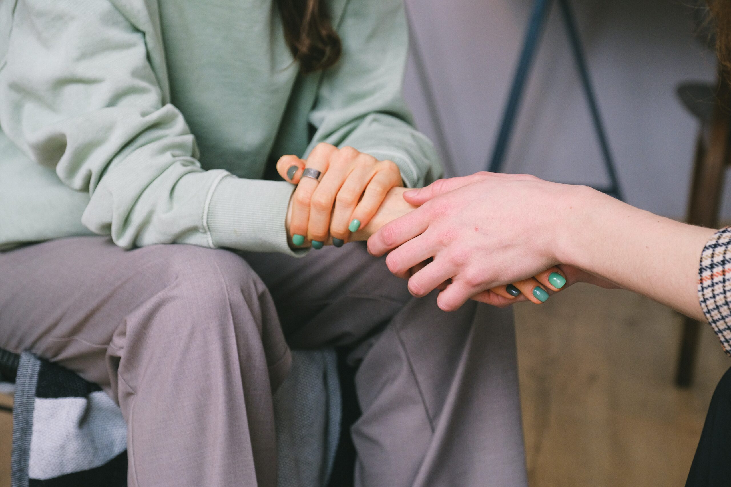 Two people sitting across from one another clasping hands