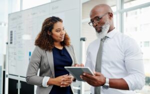 Older professional Black man discussing work with a younger black female colleague