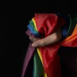 LGBTQ+ flag held tightly in a black fist