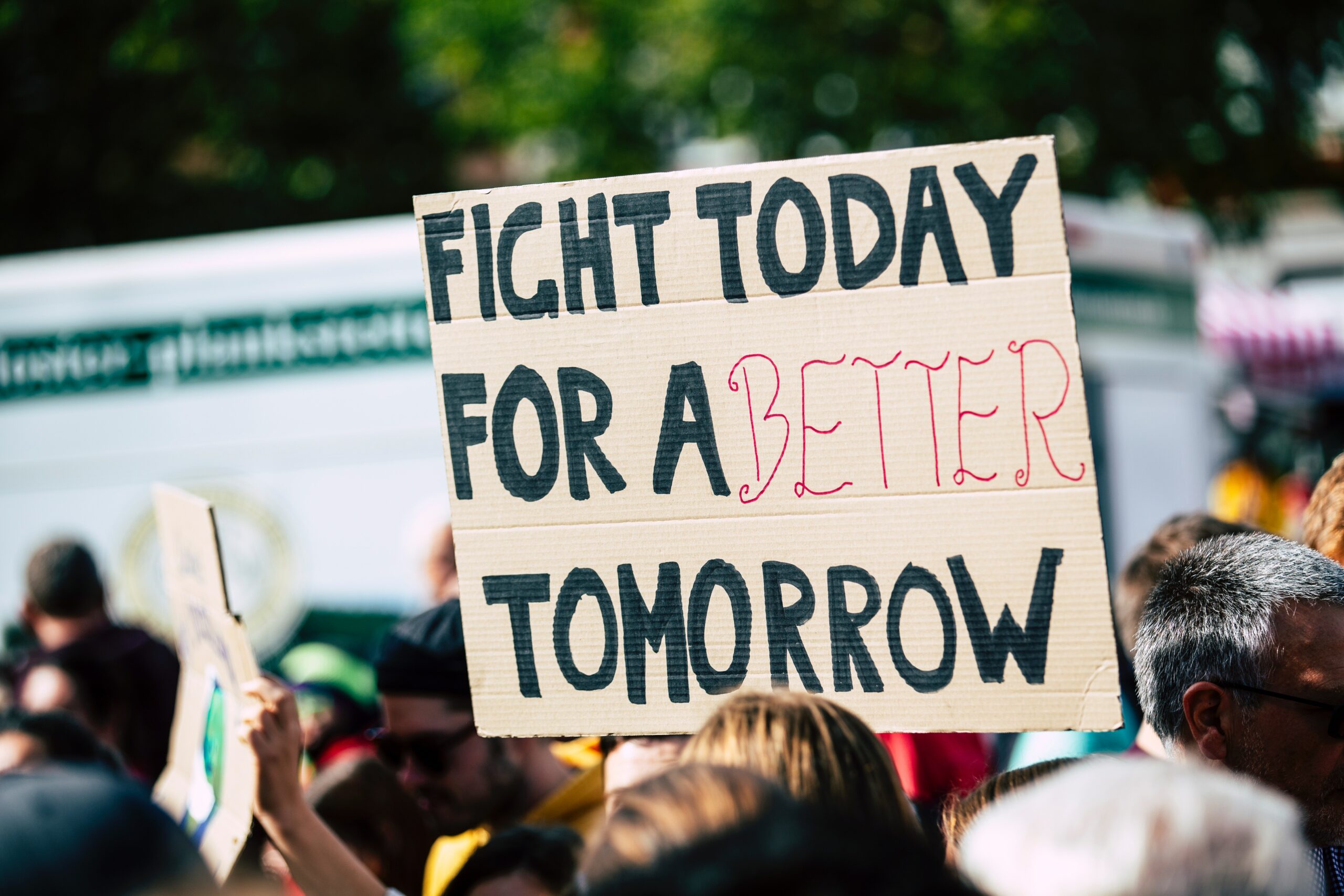 A cardboard sign being held up saying "fight today for a better tomorrow".