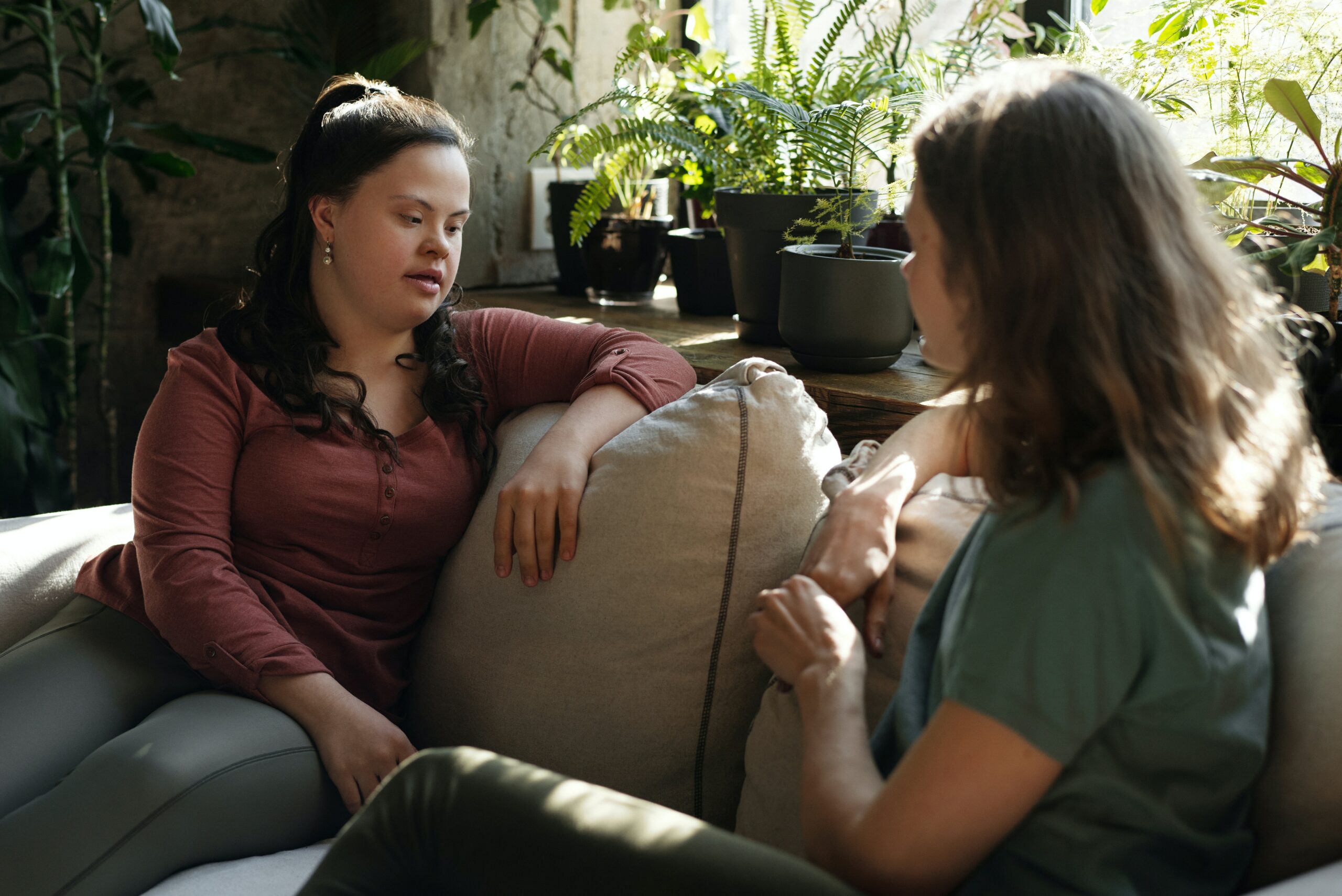 Two women sitting on a sofa talking.