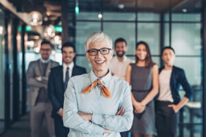 Team standing behind their feminine, middle aged office leader