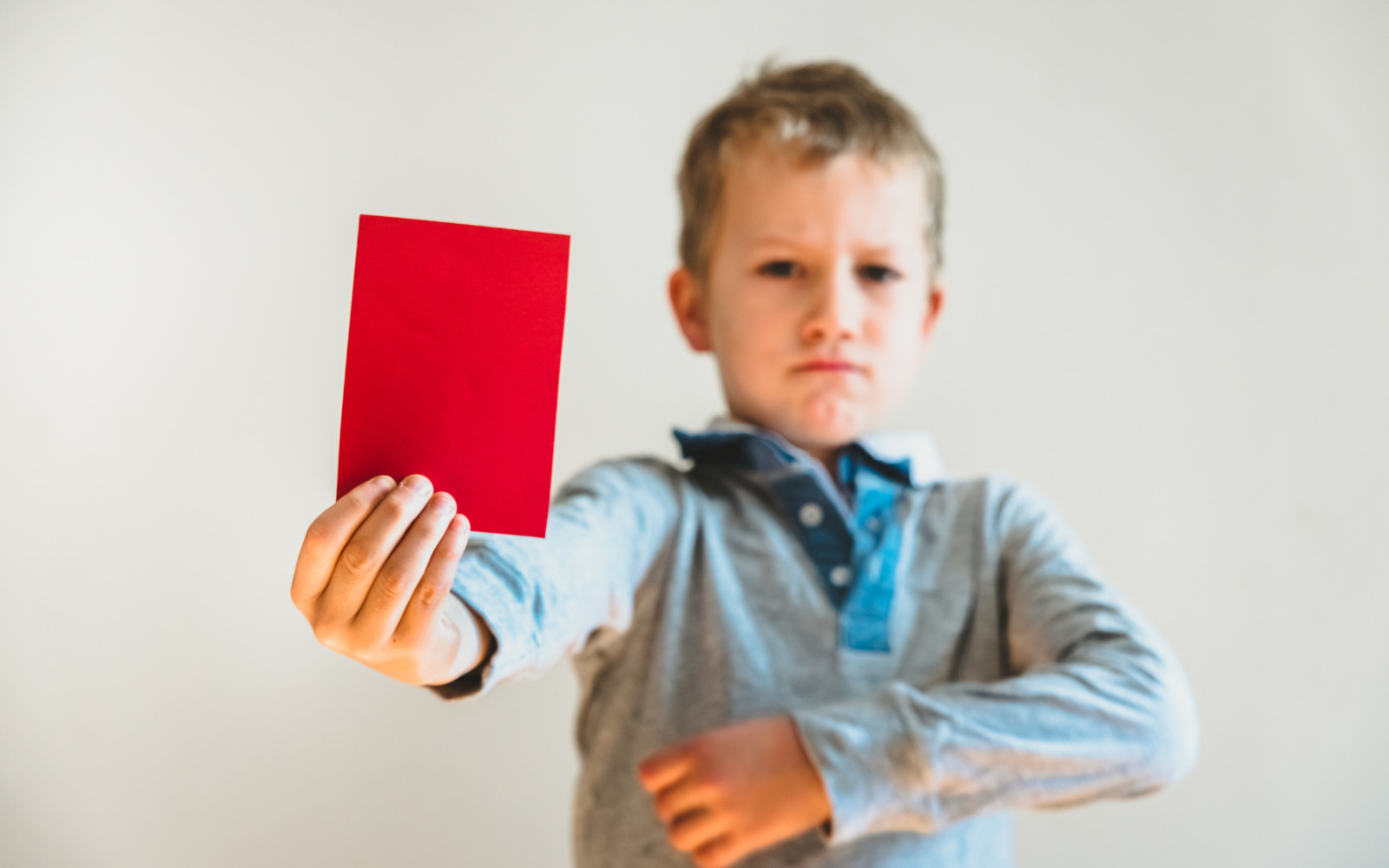 A young boy holding up a red card.