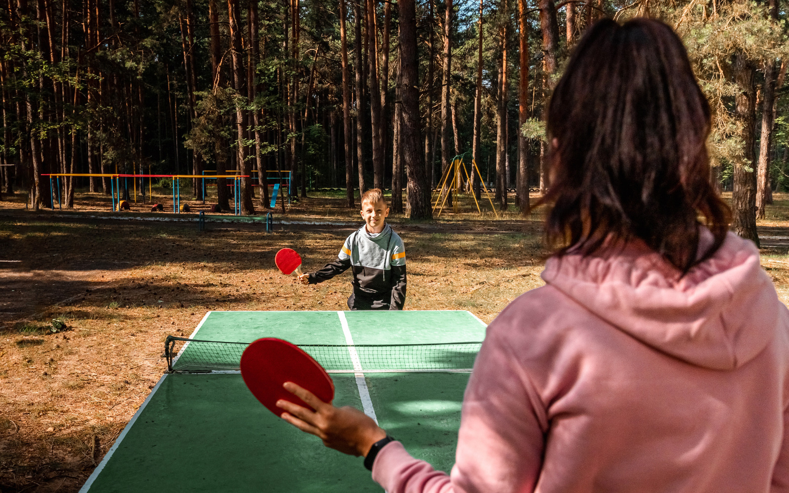 A young boy playing table tennis with an older woman.