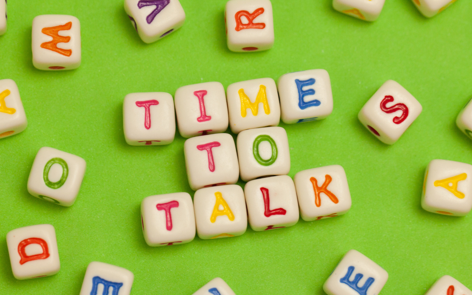 Small colourful blocks spelling our 'Time to Talk' on a green background.