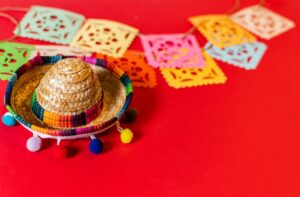 on a red background a colourful hat and various papercut square shapes for the national hispanic heritage month festival