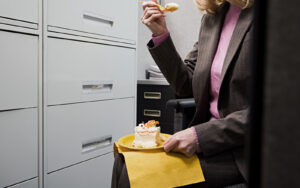Person eats cake secretly on their own in an office