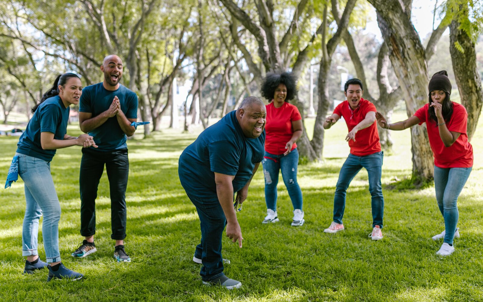 A diverse group of people in a park playing a ball game.