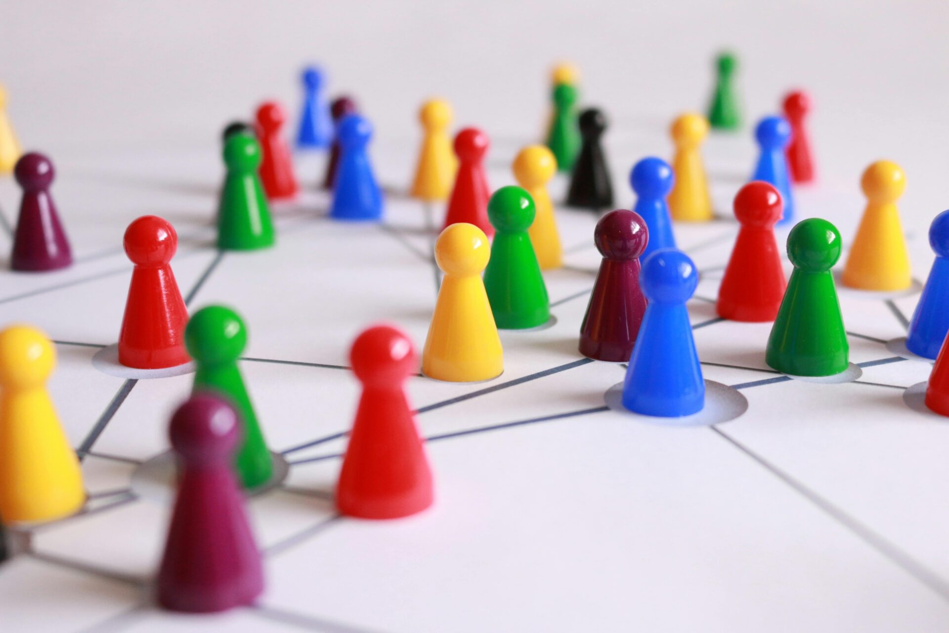 An image of dozens of brightly coloured chess pieces over a white surface with lines between them.