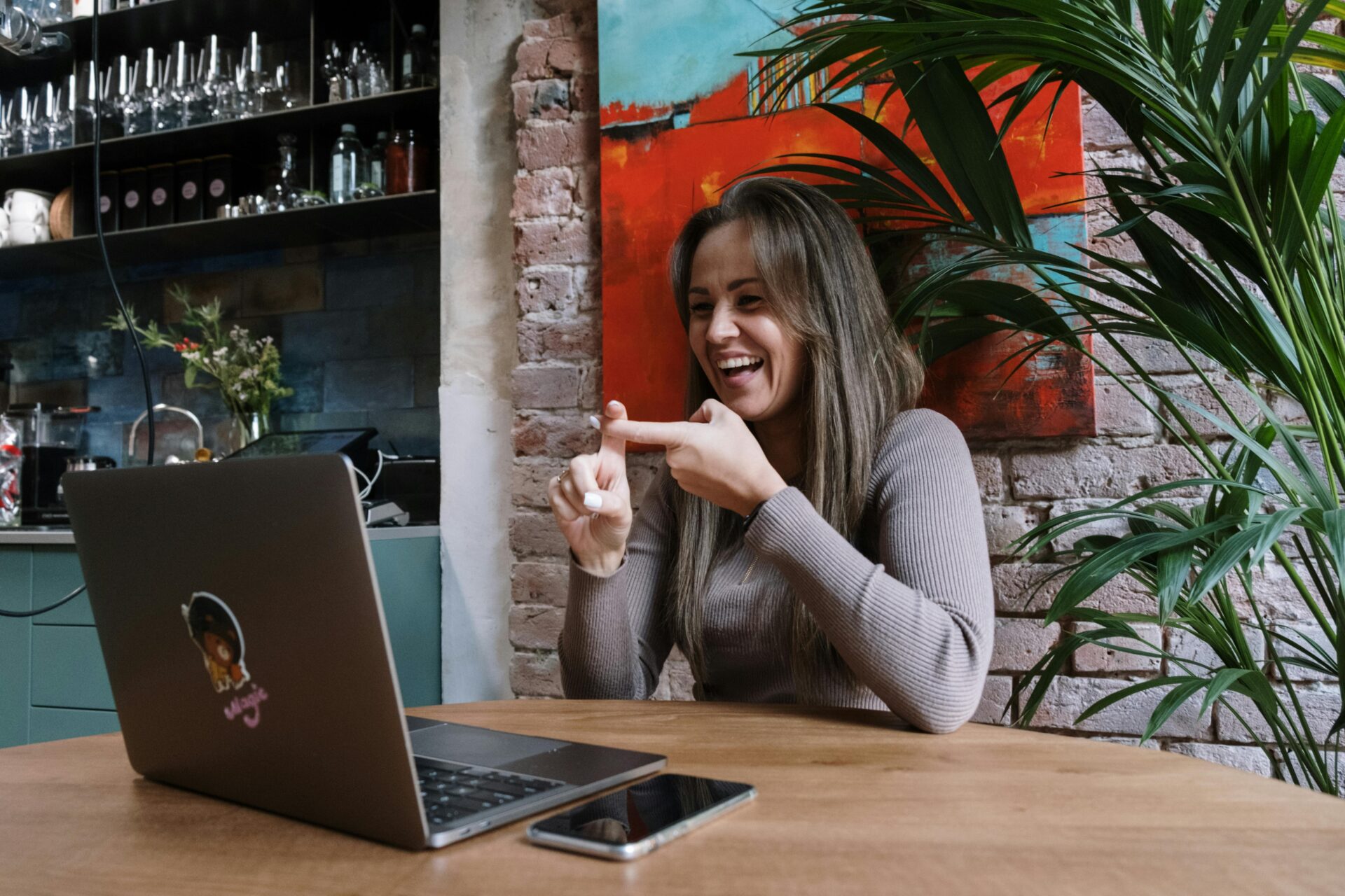 An office worker in a grey sweater signing to an open laptop.