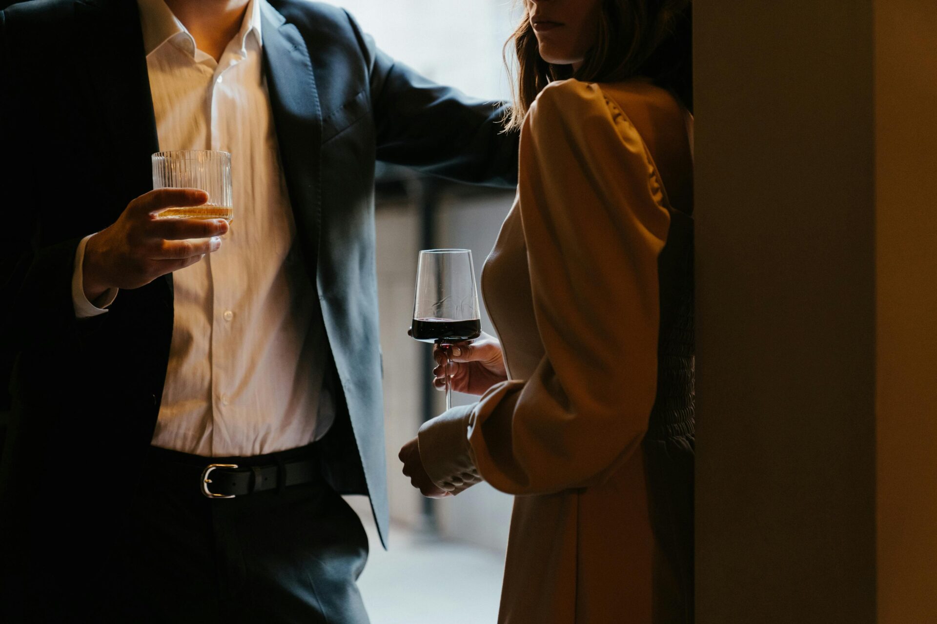 Woman in White Dress And Man In A Suit Holding Drinking Glasses