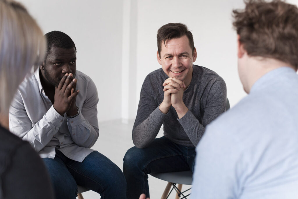 smiling man sitting and talking to his friends