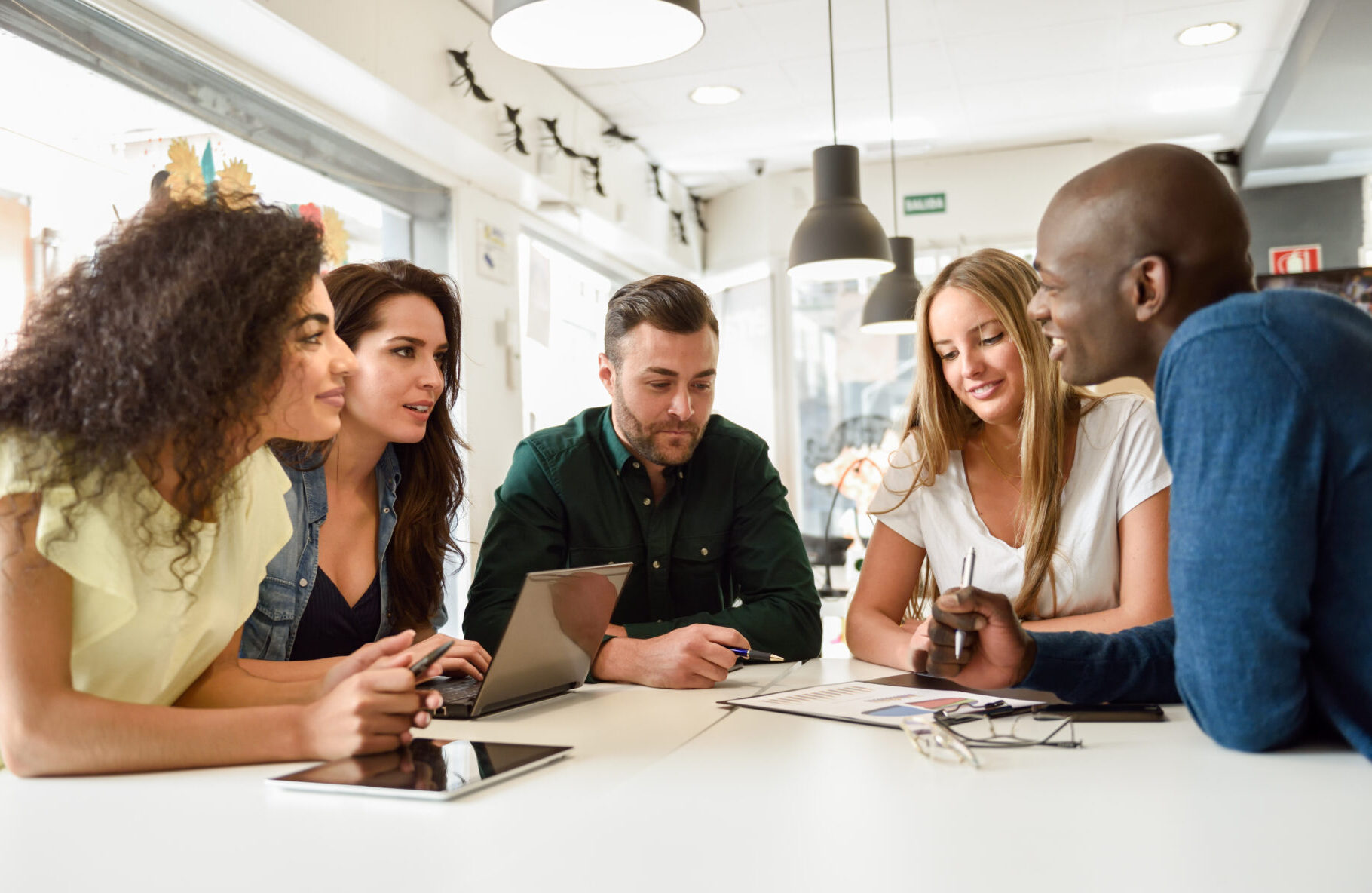 Multi-ethnic group of young professionals talking at a table